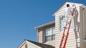 Professional painter applying exterior paint to a home in mild weather conditions