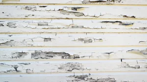 Close-up of exterior paint cracking and peeling on a home exposed to harsh weather