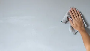 Hand wiping chalk from painted wall