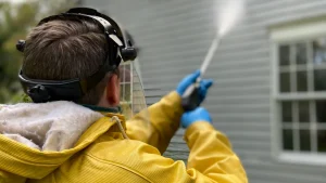 Professional power washing a home’s exterior surface before painting