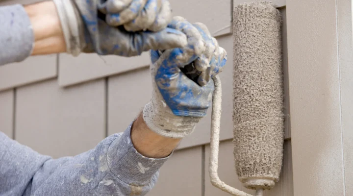Painter applying smooth siding paint coat