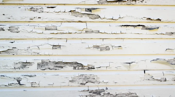 Close-up of exterior paint cracking and peeling on a home exposed to harsh weather