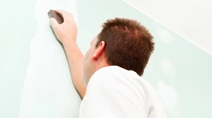 Wall being sanded to fix roller marks
