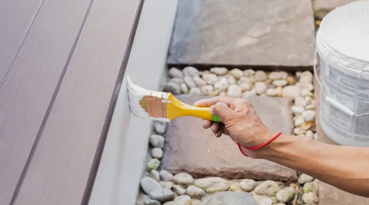 Painter applying acrylic exterior paint to siding