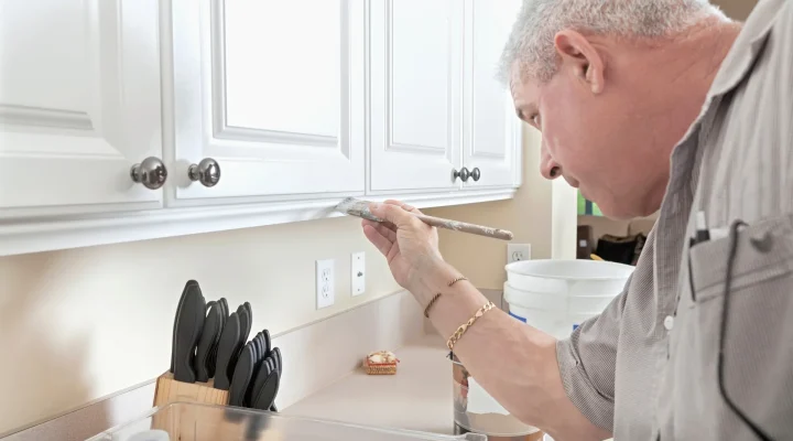 Painter painting kitchen cabinets without removing the doors
