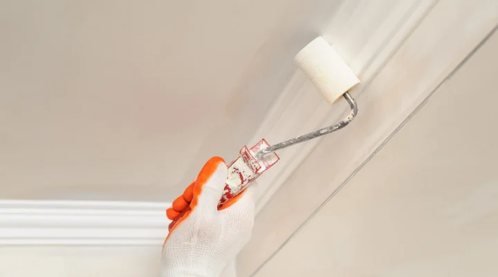 Painter applying paint to an interior ceiling