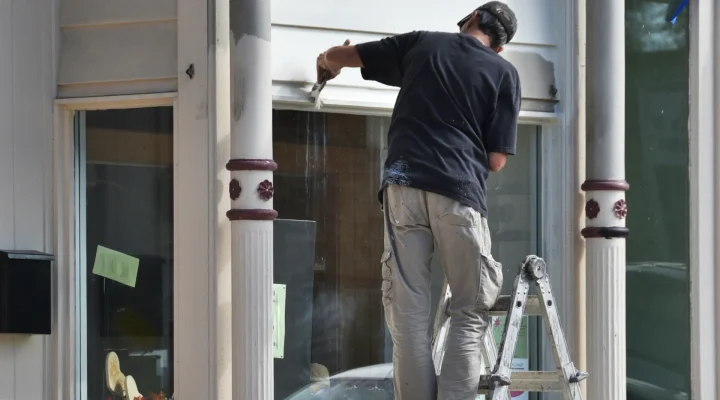 Painter working on home exterior in summer